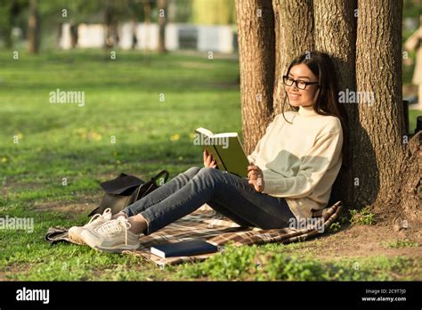 Niña leyendo bajo un árbol fotografías e imágenes de alta resolución