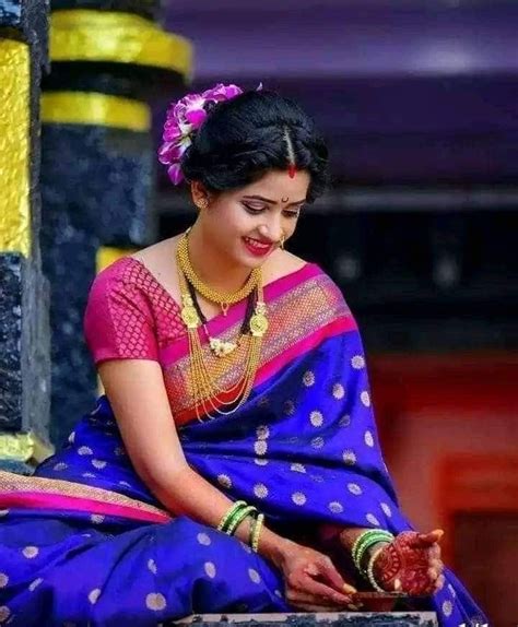 A Woman In A Blue And Pink Sari Sitting On The Ground With Her Hands