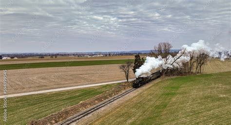 Vintage locomotive train chugging along railroad tracks in a scenic ...