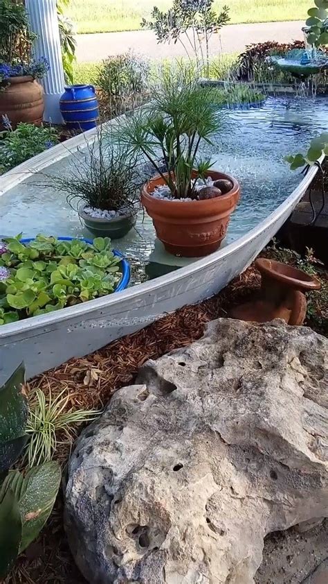 A Boat That Is Sitting On The Ground Near Some Plants And Rocks In