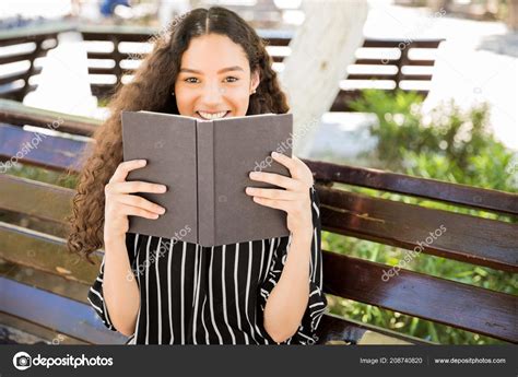 Pretty Girl Holding Book Front Her Face Smiling While Sitting Stock