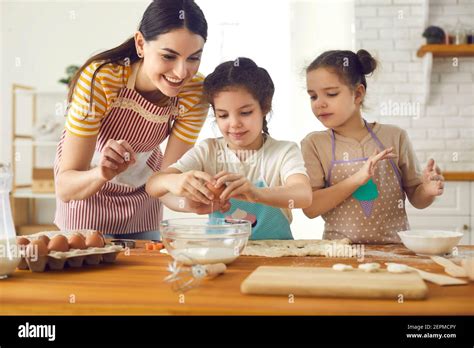 Feliz Madre Y Curiosas Hijas Haciendo Masa Para Galletas En La Cocina