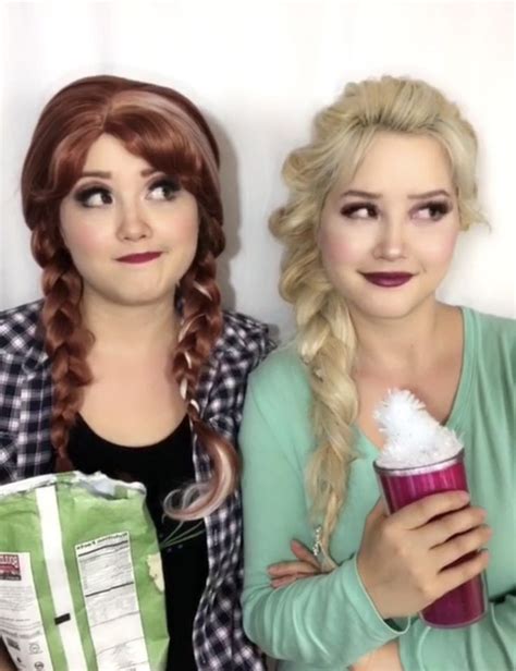 two women with braids are posing for the camera and one is holding a drink