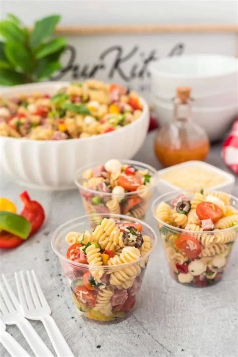 Four Plastic Cups Filled With Pasta Salad On Top Of A Table Next To