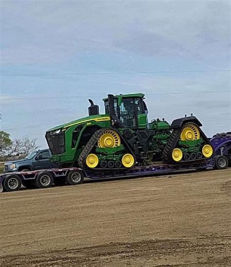 A Tractor Trailer With Two Large Tractors On It S Flatbed