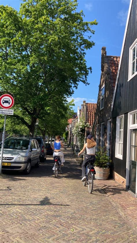 Two People Riding Bikes Down A Cobblestone Street