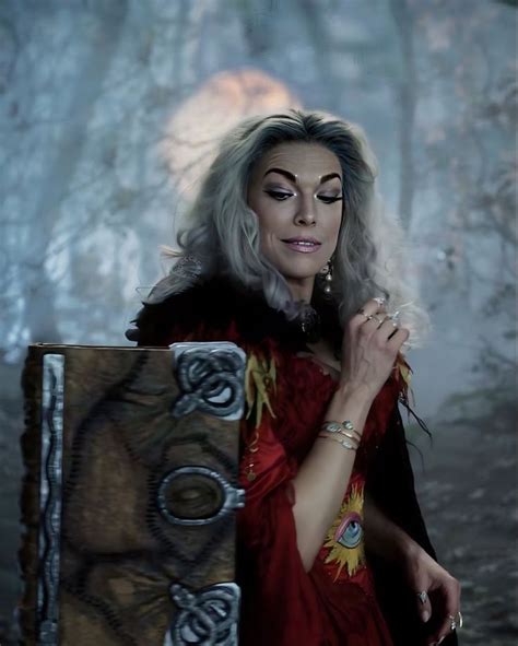 a woman with grey hair and makeup holding a box in front of her face,