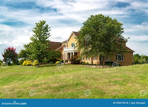 Large Brick Country House With Trees And Expansive Front Lawn Stock