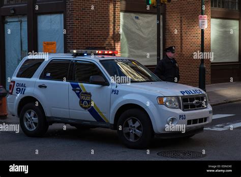 A uniformed Philadelphia Police officer stands beside a police vehicle ...