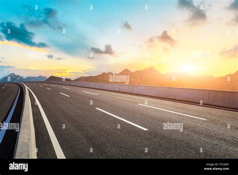 Empty Asphalt Road And Mountains With Beautiful Clouds At Sunset Stock