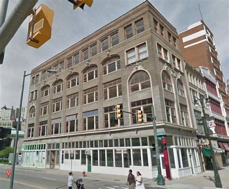 People Crossing The Street In Front Of An Old Brick Building With Many