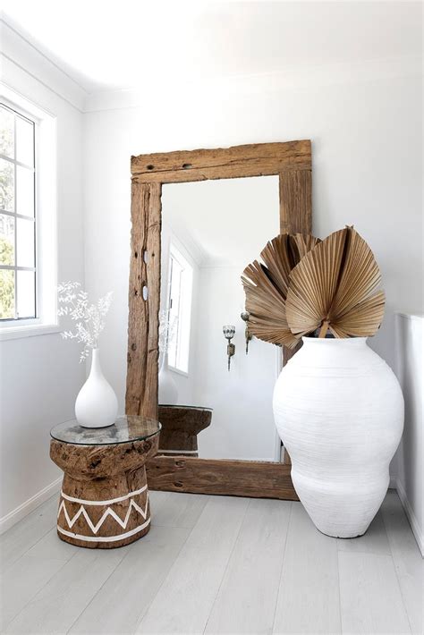 A White Vase Sitting On Top Of A Wooden Table Next To A Mirror In A Room