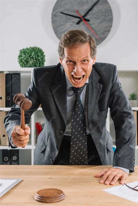 Free Photo | Furious mature lawyer giving verdict by hitting mallet at desk