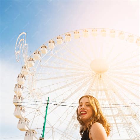 Free Photo Smiling Young Woman In Front Of White Giant Ferris Wheel