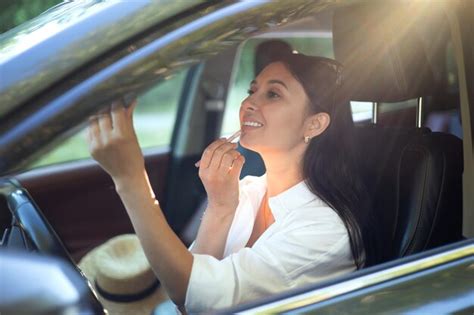 Uma Jovem E Linda Motorista Faz Maquiagem Sentada Ao Volante De Seu