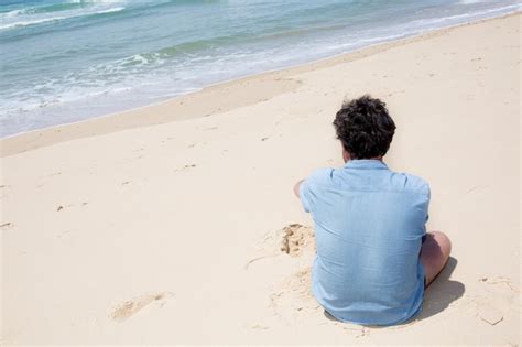 Hombre Solo Sentado En La Arena De La Playa Foto Premium