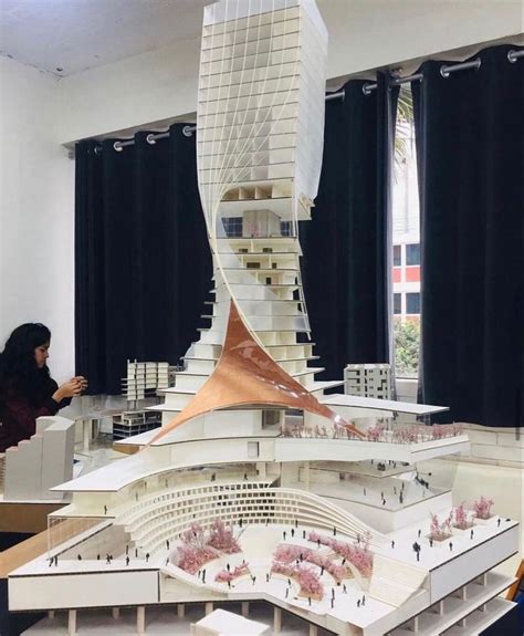 A Model Of A Building With People Standing Around It