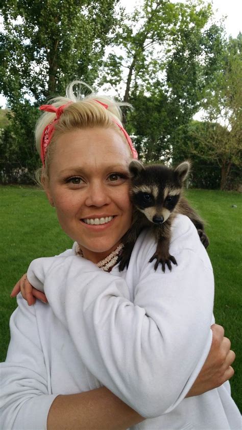 A Woman Holding A Small Raccoon In Her Arms