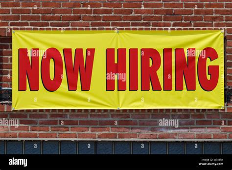 Now Hiring Bright Yellow Banner Sign With Red Print I Stock Photo Alamy