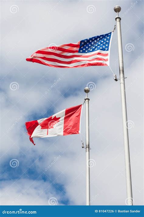 American and Canadian Flag on Poles Hanging on a Flag Pole in Th Stock ...