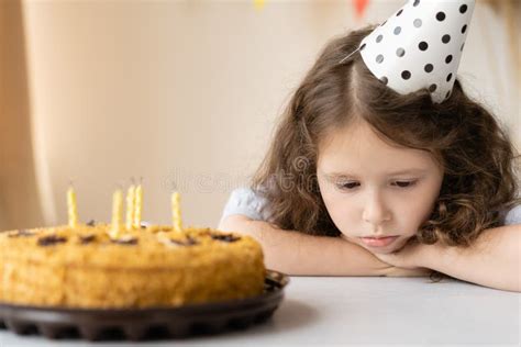 Cute Girl Is Sad On Her Birthday In Front Of Her Is A Table On Which A Festive Cake With