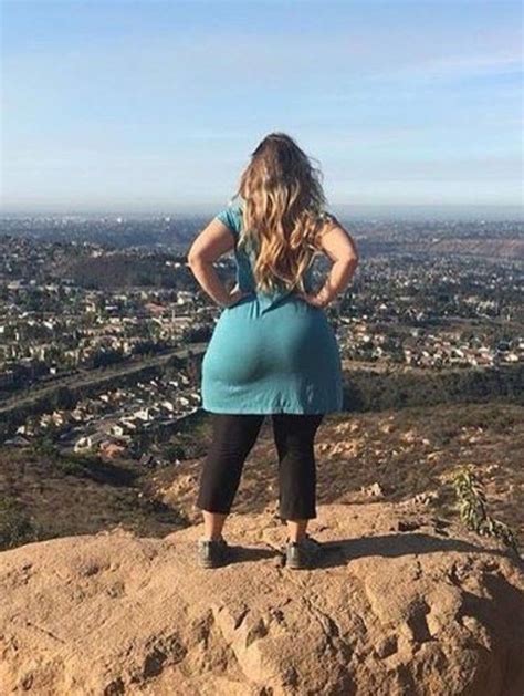 A Pregnant Woman Standing On Top Of A Rock Looking At The City Below