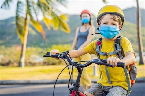 Niño de la escuela activa y su madre con máscara médica y casco de