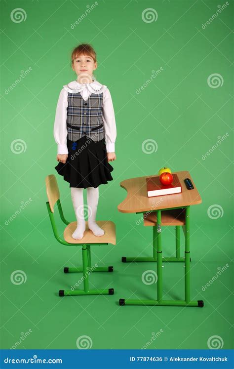 Fille Dans Luniforme Scolaire Se Tenant Sur Une Chaise Photo Stock