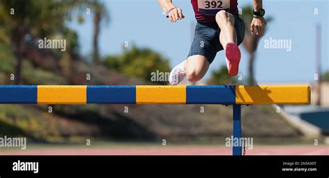 Athlete Running A Hurdle Race In A Stadium Runner Jumping Over A