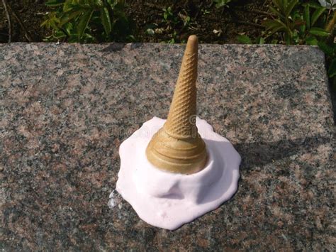 Dropped Ice Cream Cone Melting On Ground In Summertime Stock Photo