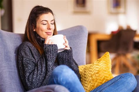 Happy Woman Drinking Tea While Relaxing In The Armchair At Home Stock