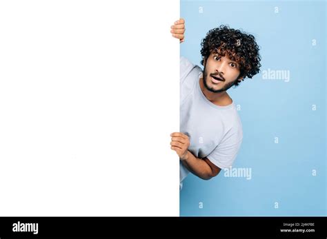 Excited Indian Or Arabian Confused Curly Guy Peeking Out From Behind