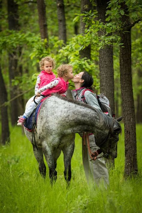 Girls Enjoying Horseback Riding In The Woods With Mother Young Pretty