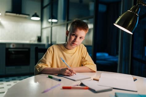 Porträt eines rothaarigen Schülers der zu Hause lernt und am Tisch