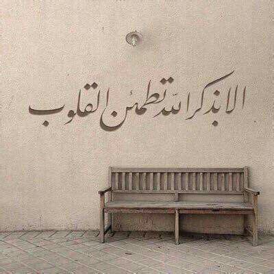 A Bench Sitting In Front Of A White Wall With Arabic Writing On The