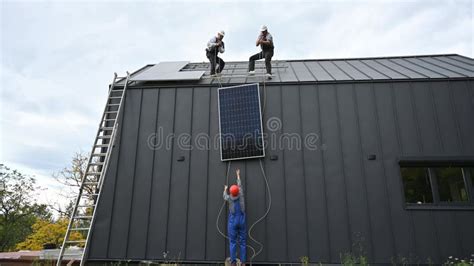 Workers Lifting Up Photovoltaic Solar Module While Installing Solar