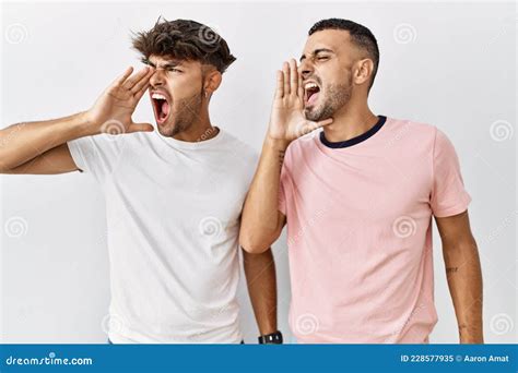 Jeune Couple Gay Debout Sur Un Fond Isolé Criant Et Hurlant Haut Et Fort à Côté De La Main Sur