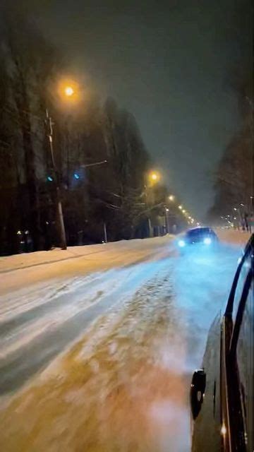 Two Cars Driving Down A Snowy Road At Night