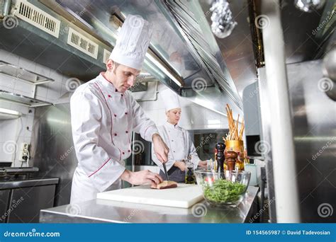 Cozinheiro Chefe Que Corta A Carne Na Placa De Desbastamento Faca