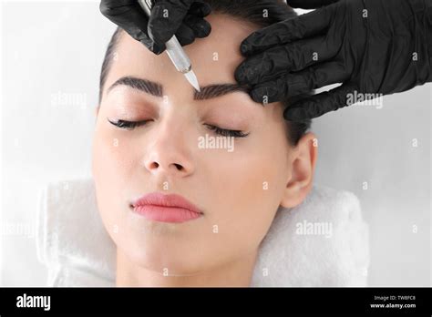 Young Woman Undergoing Procedure Of Eyebrow Permanent Makeup In Beauty