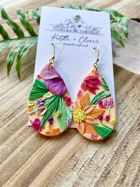 A Pair Of Earrings With Flowers Painted On Them Sitting On Top Of A