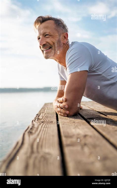 Happy Mature Man Leaning On Pier At Lake Stock Photo Alamy