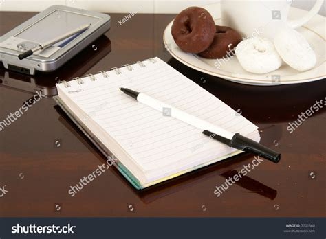 Office Desk With Notepad Pda Pen Coffee And Donuts Stock Photo