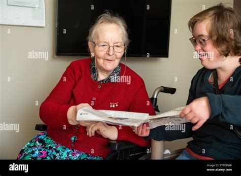 Happy Moment Between An 85 Yo Mother Reading A Newspaper With Her