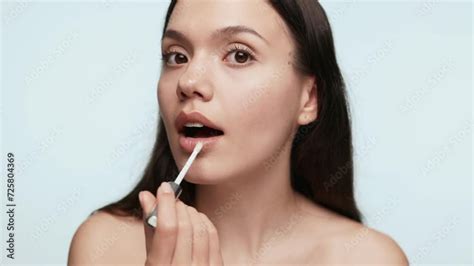 Close Up Of A Beautiful Young Woman In Her 20s Applying Lip Balm As If