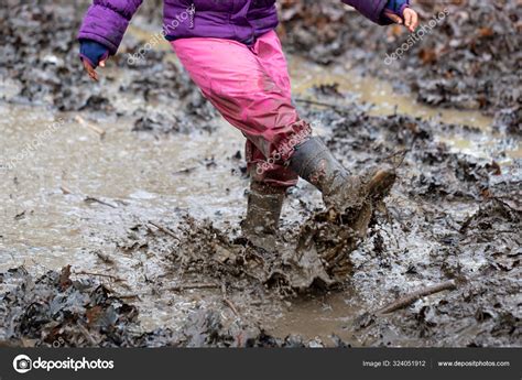 Young children playing in a mud puddle Stock Photo by ©MagicBones 324051912