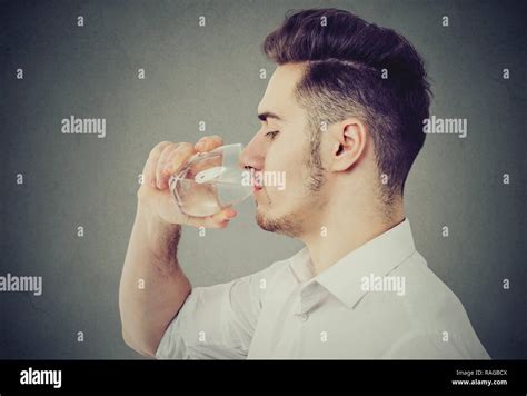 Side View Of Modern Man In White Shirt Drinking Water From Glass On