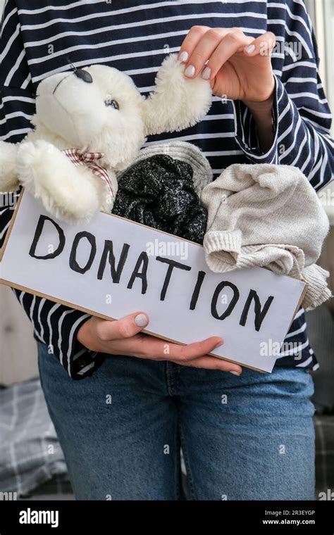 Female Volunteer Holding Donation Box With Old Used Toys And Clothes Indoors Happy Charity