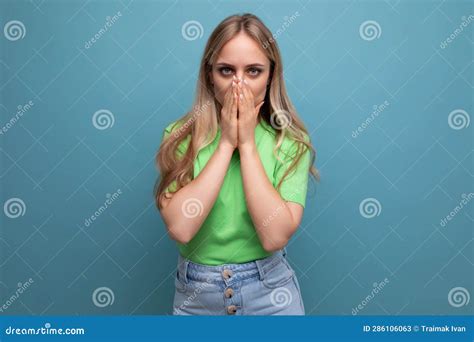 Blond Young Woman In Casual Attire Covered Her Mouth With Her Hands On A Blue Isolated