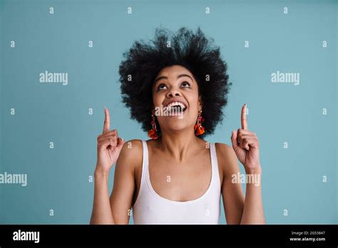 Excited African American Girl Smiling And Pointing Fingers Upward Isolated Over Blue Background